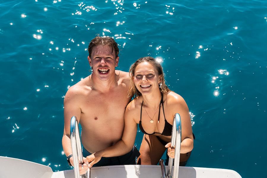 A couple climbing out of the water and onto a boat in the Whitsundays