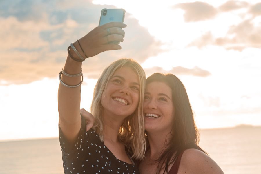 Girls taking a selfie together on the beach at sunset