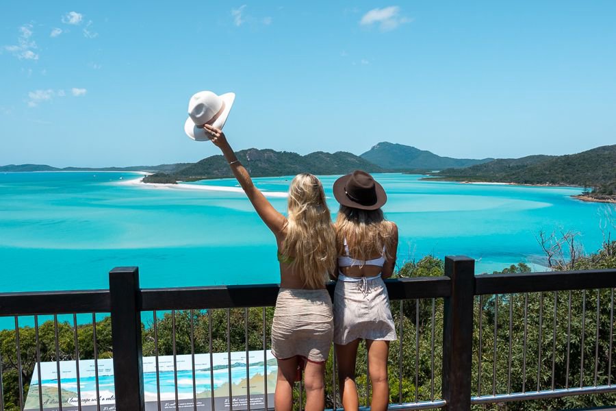 Two women overlooking the turquoise waters and swirling sands of Hill Inlet at Whitehaven Beach in the Whitsundays