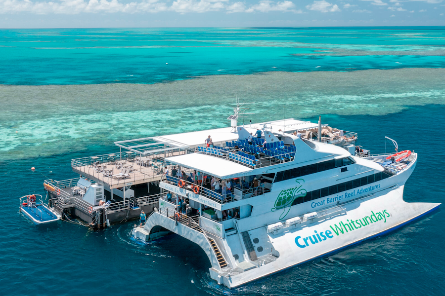 Aerial view of a Cruise Whitsundays catamaran docked at a Great Barrier Reef pontoon surrounded by vibrant turquoise reef waters