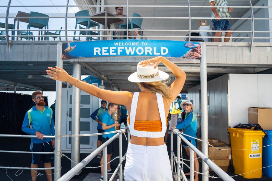 Guest walking toward the Reefworld pontoon entrance under a “Welcome to Reefworld” sign at the Great Barrier Reef
