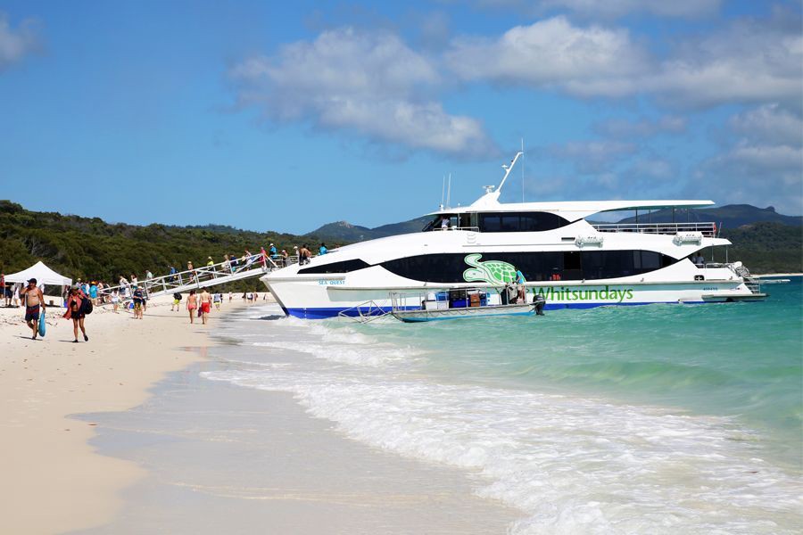 Cruise Whitsundays catamaran anchored at Whitehaven Beach with passengers disembarking onto the white sand and turquoise water