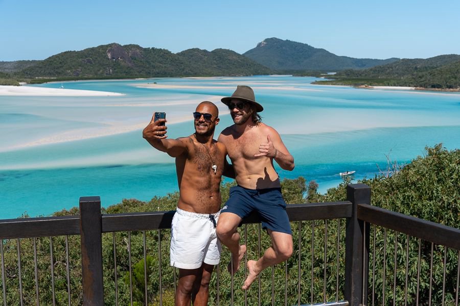 Two friends taking a selfie at Hill Inlet Lookout with the swirling white sands and turquoise waters of the Whitsundays behind them