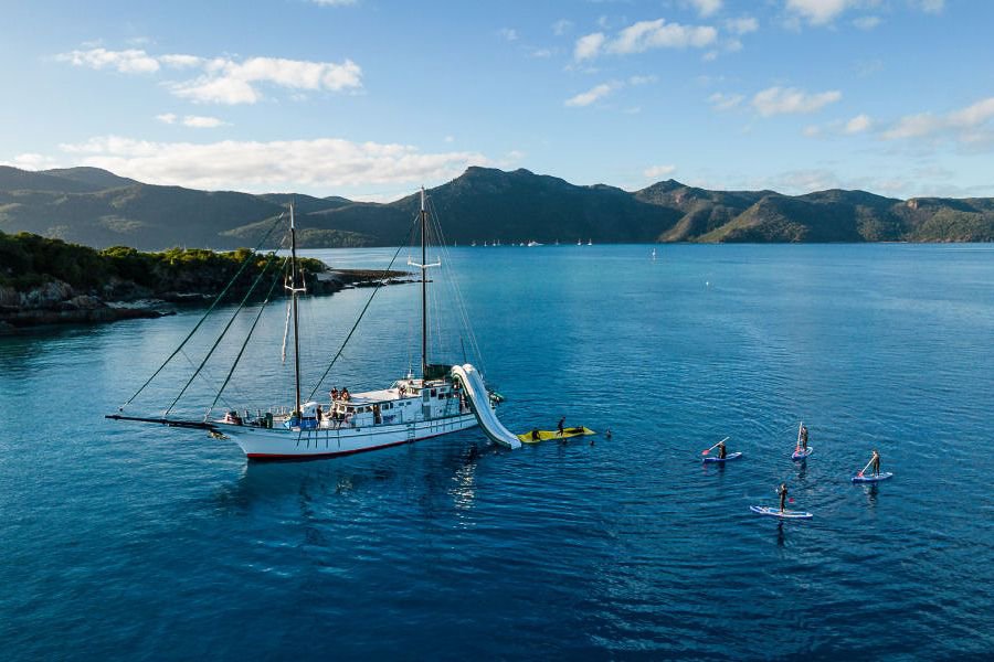 New Horizon anchored with guests paddleboarding and enjoying water activities in the Whitsundays 