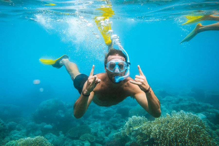 Guest snorkelling over coral reef during a Whitsundays sailing experience 