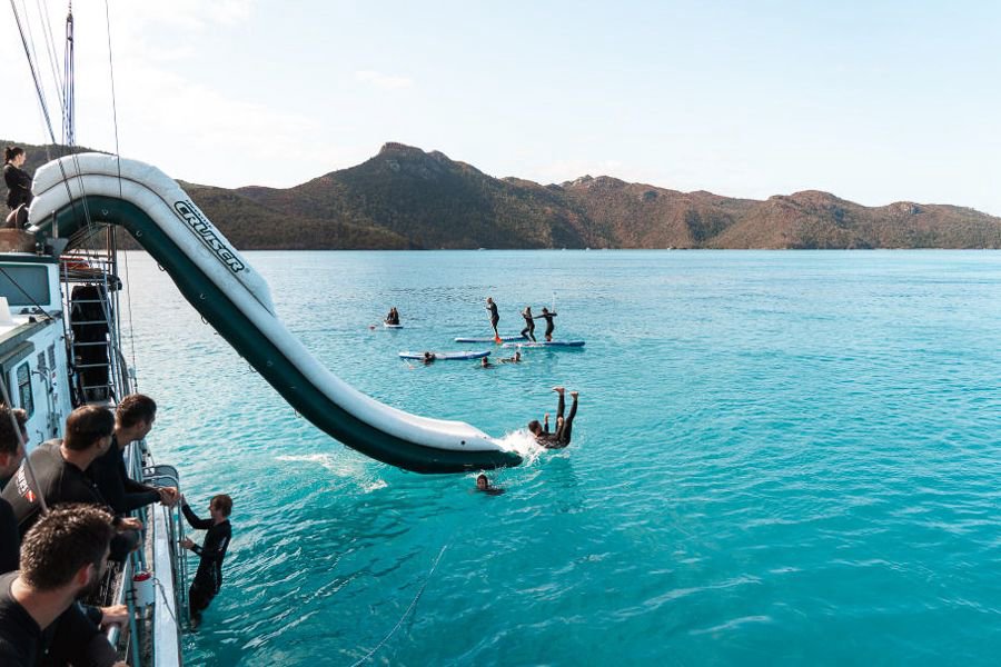Guests enjoying the onboard waterslide off New Horizon in the Whitsundays 