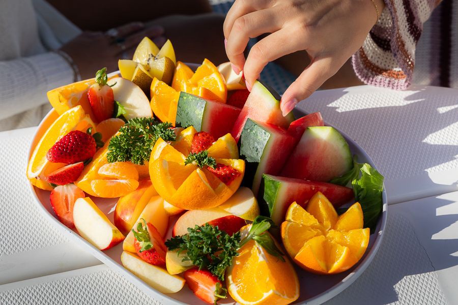 Close-up of a fresh tropical fruit platter with watermelon, oranges, strawberries and apple slices served onboard a Whitsundays sailing trip