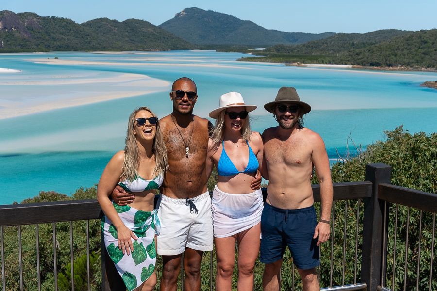 Group of friends posing at Hill Inlet lookout overlooking the swirling white sands and turquoise waters of Whitehaven Beach in the Whitsundays.