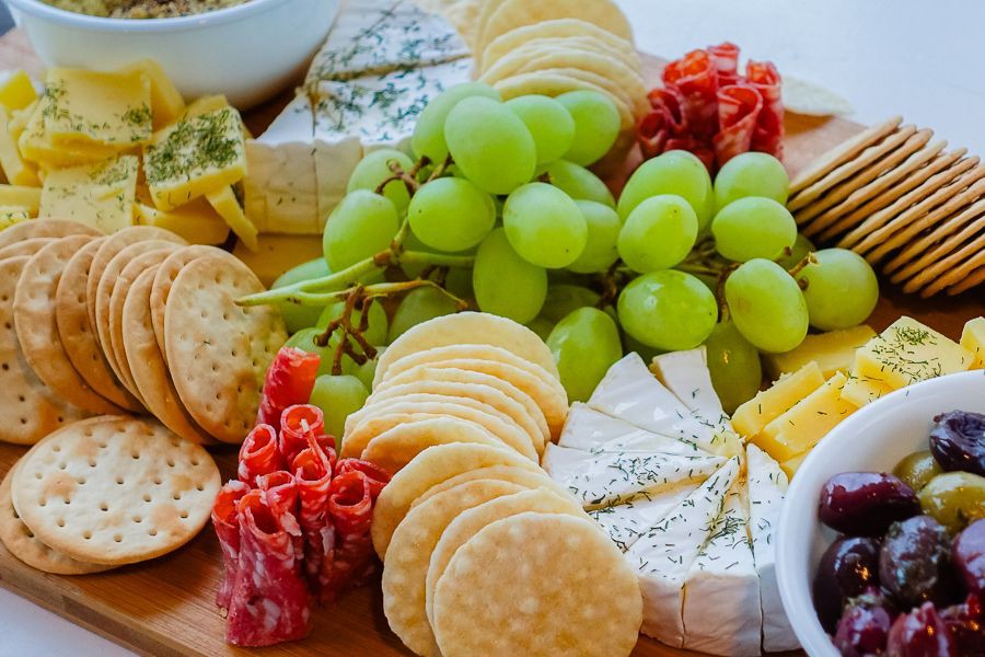 Close-up of a gourmet cheese and charcuterie platter with grapes, crackers, olives and cured meats served onboard a Whitsundays sailing trip
