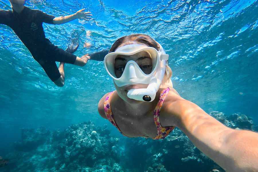 Woman snorkelling above colourful coral reef in the clear turquoise waters of the Great Barrier Reef, Whitsundays, Queensland