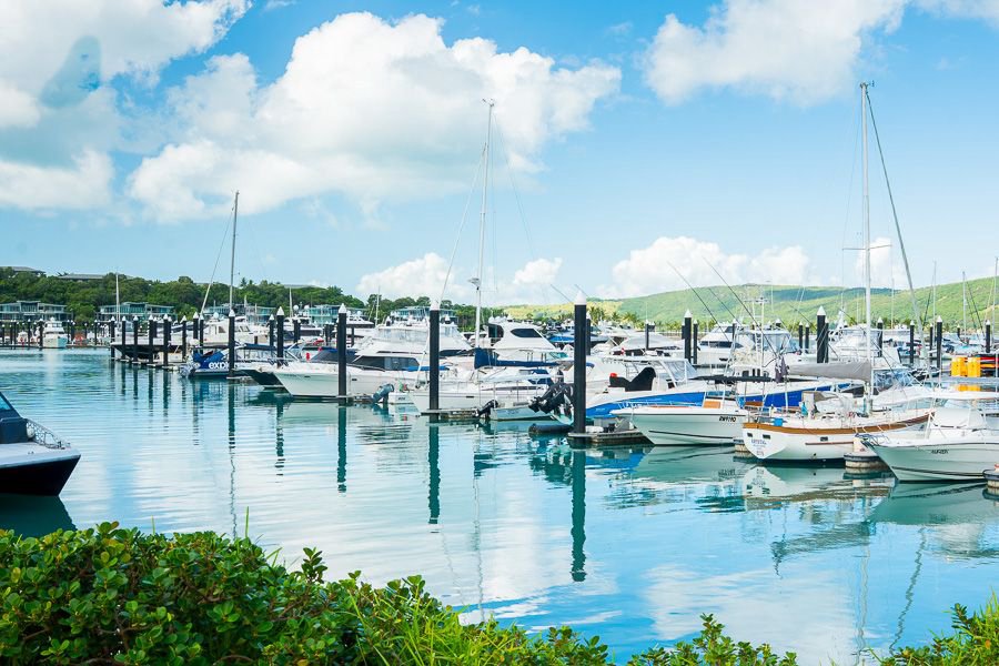 Luxury yachts and boats moored at Hamilton Island Marina on calm turquoise water under a blue sky