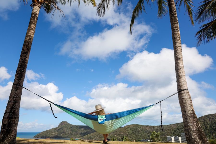 Woman relaxing in a hammock between palm trees overlooking the Whitsunday Islands