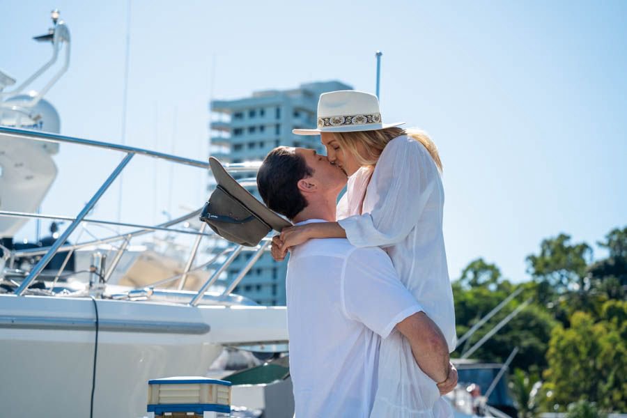 Couple sharing a kiss beside a yacht at the Hamilton Island marina in the Whitsundays