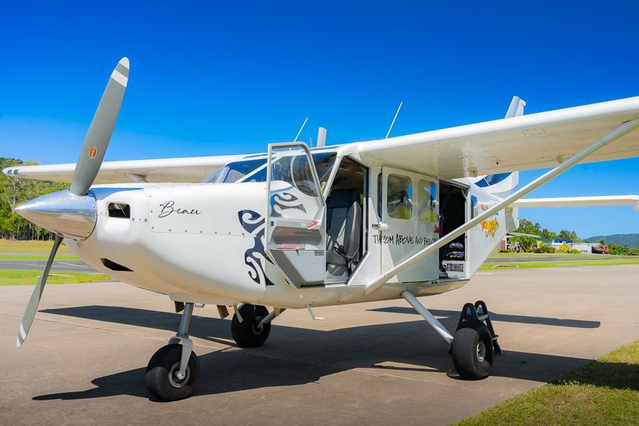Small white Ocean Rafting scenic flight plane parked on the runway with cabin door open, ready for passengers at Whitsunday Airport.