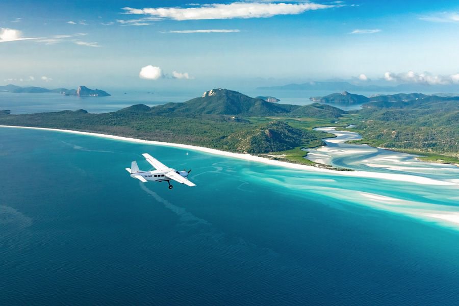 Small scenic airplane flying above the turquoise waters and swirling sands of Whitehaven Beach in the Whitsundays.
