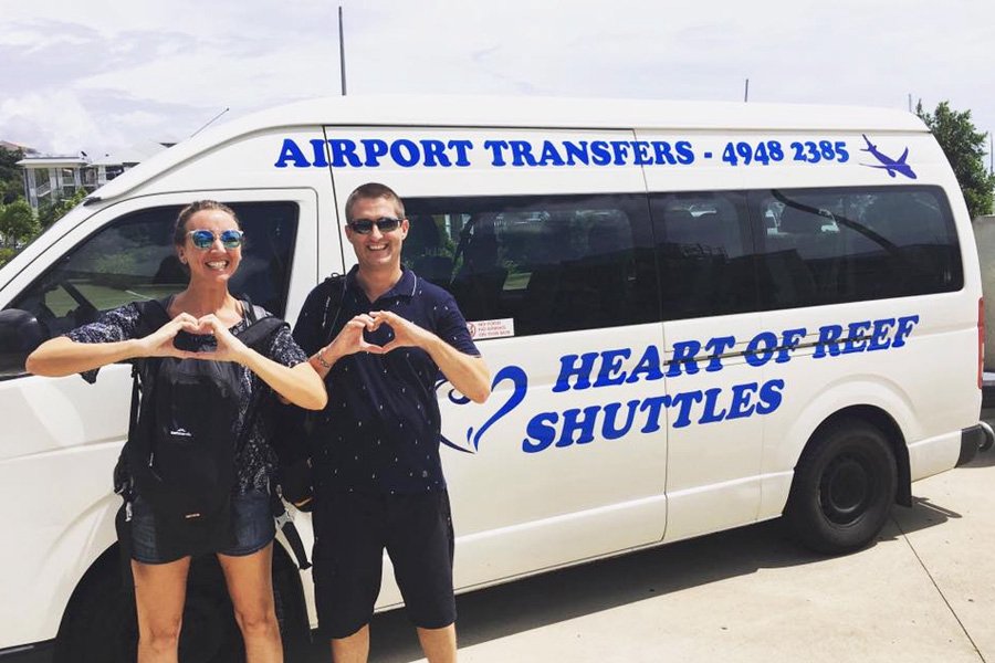 Guests standing in front of a Heart of Reef Shuttles airport transfer vehicle in the Whitsundays