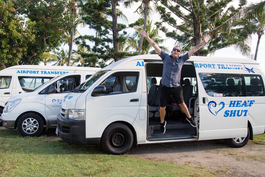 Airport transfer vehicle from Heart of Reef Shuttles in the Whitsundays with staff member welcoming guests
