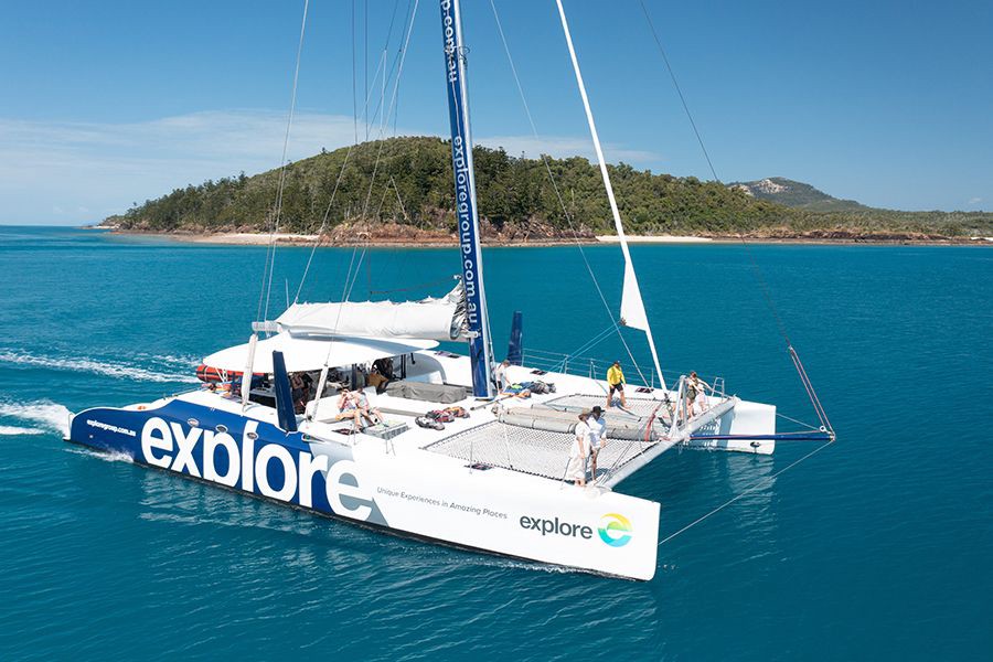 Large white catamaran sailing through turquoise water