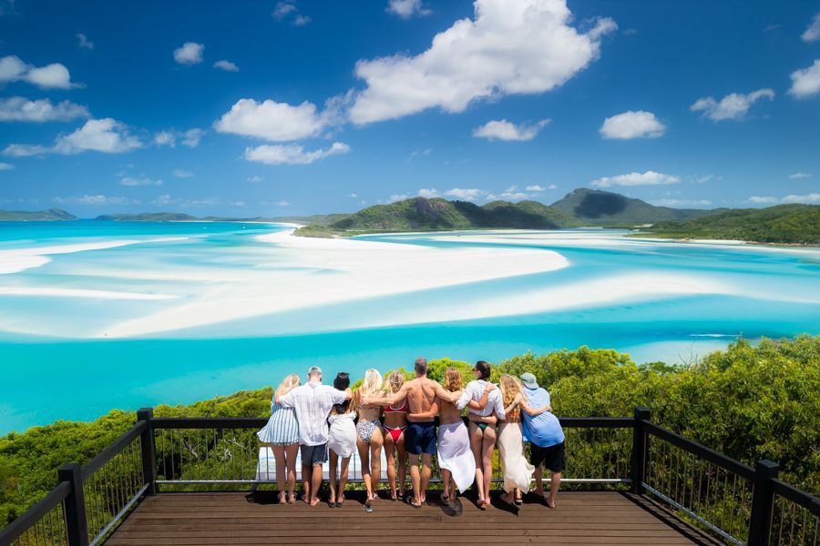Group of friends standing at Hill Inlet Lookout overlooking the swirling white sands and turquoise waters of Whitehaven Beach in the Whitsundays.