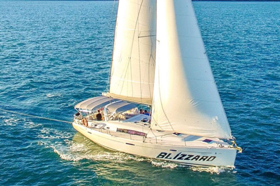Aerial view of the yacht Blizzard sailing across clear blue waters in the Whitsundays with sails fully raised on a sunny day