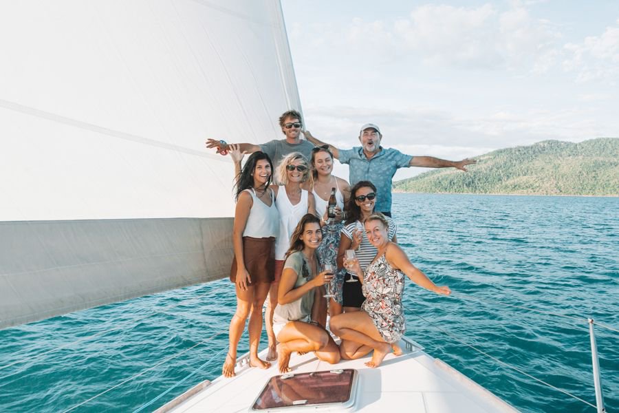 Group of friends and family smiling on the front of a Whitsundays sailing yacht