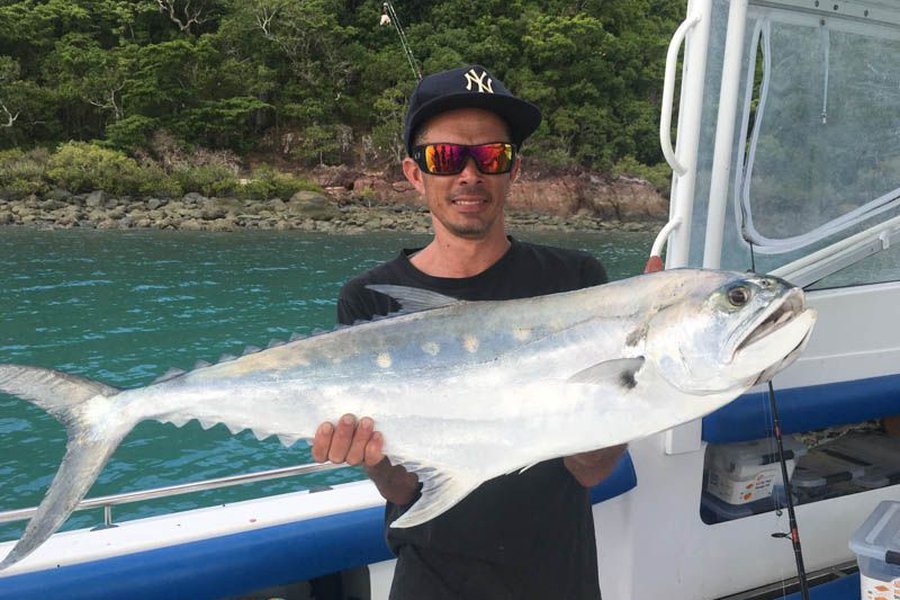 Man holding up a giant fish he caught on a whitsundays fishing charter