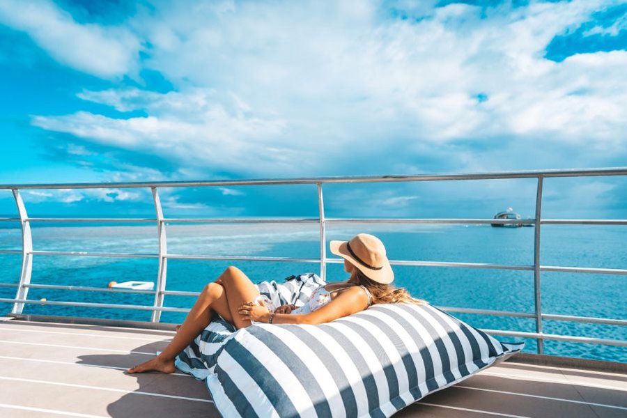 Woman relaxing on a bed bag on the sun deck of the Reefworld Pontoon Experience
