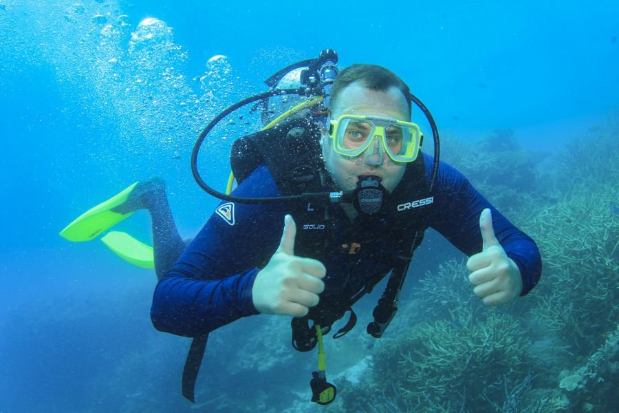 scuba diver posing for underwater camera amongst corals 