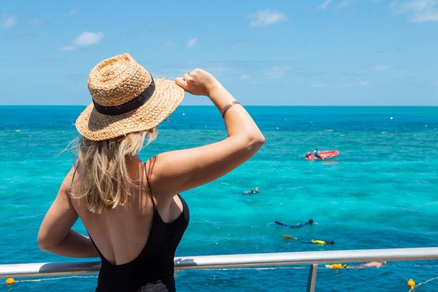 woman admiring turquoise waters over a reef site from the deck of a boat