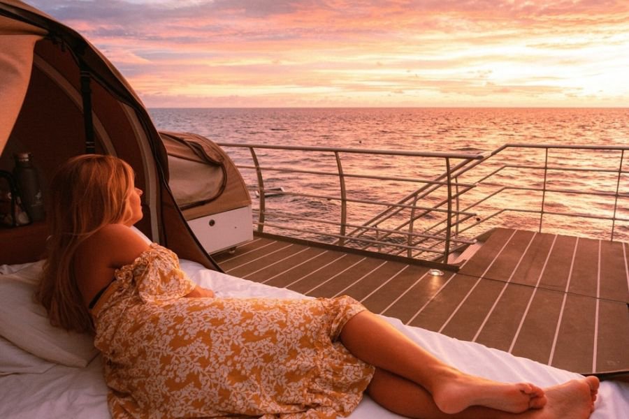 woman lying on an outdoor reefbed watching the sunrise on Reefsleep