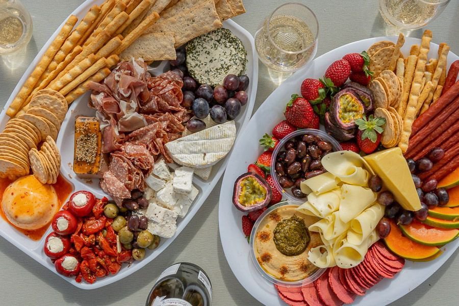 two platters filled with meat, cheese, fruits, and champagne 